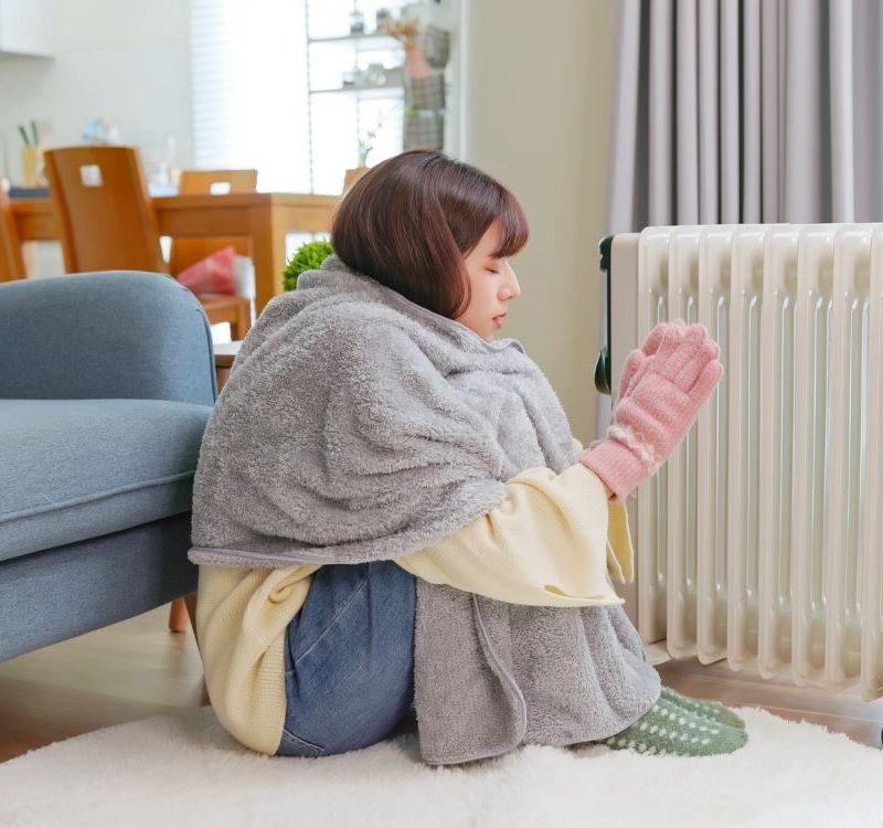 woman wrapped up next to heating