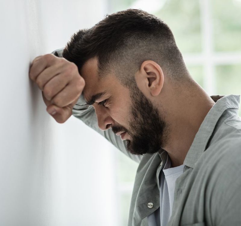 sad man leaning on wall