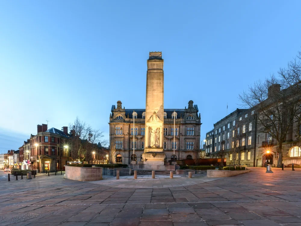 A photo of Preston Cenotaph, against a dusk sky. The cenotaph is lit up from below.