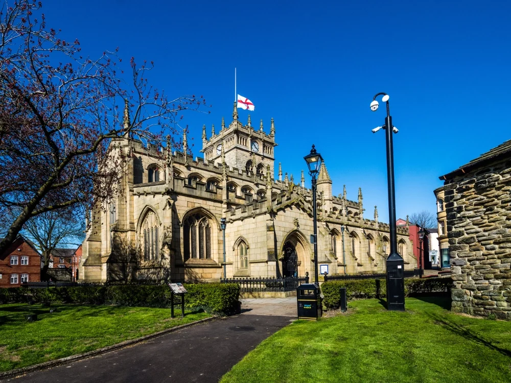 St Mary's Church in WIgan with grass in the foreground and a clear blue sky behind.